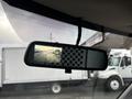 The rearview mirror of a 2022 GMC Savana displaying a backup camera image with vehicles visible in the distance