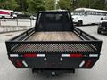 A black 2020 Ford F-350 SD flatbed truck with a wooden bed and metal mesh sides parked in a lot