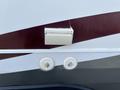 A 2013 Outdoor Wind River trailer with a white and maroon exterior featuring a small storage compartment and two circular connections below