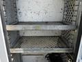 Metal shelving units inside a 2004 Freightliner M2 truck with a diamond-patterned design and multiple levels for storage