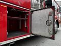 The image shows the open side compartment door of a red 1991 Sutphen Deluge fire truck revealing shelves inside