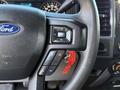 Close-up of a steering wheel in a 2018 Ford F-150 showing audio control buttons and a small red keychain attached