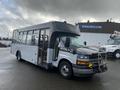 A 2018 Chevrolet Express bus with a black and white exterior and a front-mounted grill guard parked with visible side windows and door