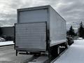 A 2019 Hino 338 24-foot cube truck with a white exterior and a roll-up rear door is parked on a snowy street