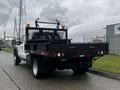 A 2015 Ford F-550 truck with a flatbed and a black mesh rack on the rear featuring orange lights and various hardware attachments