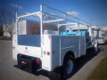 A 2011 International DuraStar 4300 utility truck with a white exterior and ladder racks on top designed for construction or maintenance work