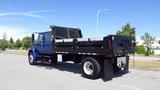 A blue 2012 International DuraStar 4300 dump truck with a black dump bed is parked on a concrete surface