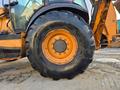 Close-up view of a large, rugged tire from a 2015 Case 590SN loader showcasing deep treads and a central hub with visible lug nuts