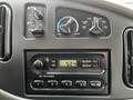 Dashboard controls and stereo system of a 2004 Ford Econoline featuring knobs for air conditioning and a digital clock display on the radio