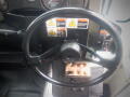 Steering wheel of a 2008 International 7400 with warning labels and a small wooden object on the dashboard