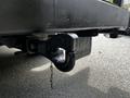 A close-up of a towing hitch under the rear of a black 2016 Ford F-550 showcasing the hook and a safety chain attached