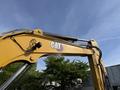 A yellow Caterpillar 306 excavator's arm with a visible CAT logo and hydraulic components