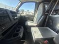 A 2007 Chevrolet Express interior with a single driver's seat and console featuring controls and cup holders