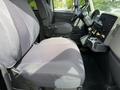 Interior of a 2011 International 4300 featuring a gray fabric driver's seat and dashboard with controls and instruments visible