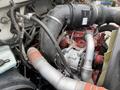 An engine compartment of a 2011 Ford F-650 featuring various pipes and components including an alternator and intake manifold
