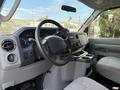 Interior of a 2011 Ford Econoline featuring a steering wheel dashboard and front seats with a center console