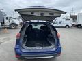 A blue 2019 Nissan Rogue with its rear hatch open revealing a spacious but empty cargo area