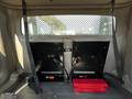 Interior view of a 2004 Freightliner M2 showing two black mounted panels with cables and a red toolbox on the floor