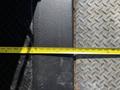 A close-up view of a measuring tape spanning a gap between two surfaces with one surface being smooth and the other covered in a diamond pattern