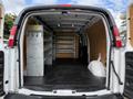 The interior of a 2018 GMC Savana with shelves and a clean, empty cargo space designed for transportation and storage