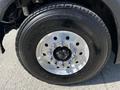 Close-up of a 2012 Freightliner M2 112 truck wheel featuring a shiny silver rim with multiple bolts and a thick black tire with the M864 label on the side