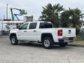 A white 2016 GMC Sierra 1500 pickup truck with chrome accents parked with its tailgate closed and a visible 4x4 emblem on the side