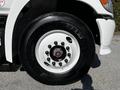 Close-up of a wheel and tire on a 2021 Hino 338 truck showing a white rim with multiple lug nuts and a black tire with brand lettering visible