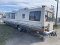 A 1987 Chevrolet Fleetwood Pace Arrow motorhome with a beige and brown exterior featuring an extended rear and large windows
