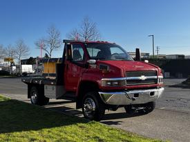 A red 2005 Chevrolet C4C042 truck with a flatbed and yellow storage box in the rear facing forward on a paved surface