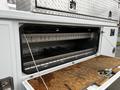 The image shows the open storage compartment of a 2004 Ford F-450 SD revealing metal shelves and wooden flooring inside