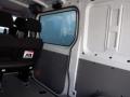 A 2016 Mercedes-Benz Sprinter interior featuring a row of black seats and a window on the side with a simple gray panel on the wall