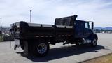 A blue 2012 International DuraStar 4300 flatbed truck with a black dump bed and dual rear wheels parked on a lot