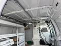 Interior of a 2008 Ford Econoline van showing shelving units and a partition wall with a metal grate