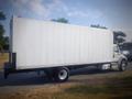 A 2016 Freightliner M2 106 medium duty truck with a large white cargo box and a black rear bumper parked on the street