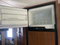 An open refrigerator with a separate freezer compartment inside a 2014 Launch 24RLS showing empty shelves and an ice tray