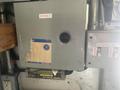 A gray electrical control box with labels indicating 12 volt and outside lights, featuring a circular opening and a worn area on the surface