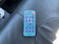 A remote control with various buttons labeled for functions like mute, menu, timer, and volume placed on a black leather surface