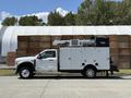 A 2023 Ford F-550 truck with a white body and a large utility box on the side equipped with a ladder and a generator on top