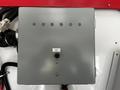 A gray control box with multiple screws and a black knob on the front