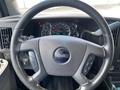 Steering wheel of a 2023 GMC Savana with control buttons and a dashboard displaying speedometer and gauges