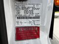 A white 2016 Ford F-550 with a vehicle identification label and a warning sticker about U-bolt tightening on its side panel