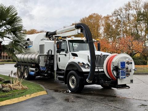 A 2014 International 7500 vacuum truck with a large tank and hoses attached for suction and drainage operations