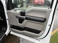 The door panel of a 2018 Ford F-150 featuring a gray and black design with a handle and storage compartment