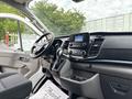 Interior view of a 2023 Ford Transit showing the steering wheel dashboard and control panel with a display screen and gear shift