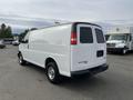 White 2012 GMC Savana van with a plain design and chrome wheels parked in a lot viewed from the rear