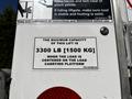 A label on a lift indicating the maximum capacity is 3300 pounds or 1500 kilograms when the load is centered on the load carrying platform