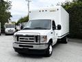 A white 2021 Ford E-450 box truck with a flat front and a large cargo area in the back is parked with the driver's side facing the viewer