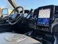 Interior view of a 2023 RAM 3500 with a large touchscreen display showing navigation and music controls along with steering wheel and dashboard elements