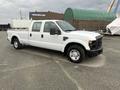 A 2010 Ford F-250 SD pickup truck in white with a cab and no visible cargo in the back parked on a solid surface