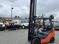 A 2011 Toyota Forklift with an orange and gray color scheme positioned prominently in the foreground with its lifting forks raised